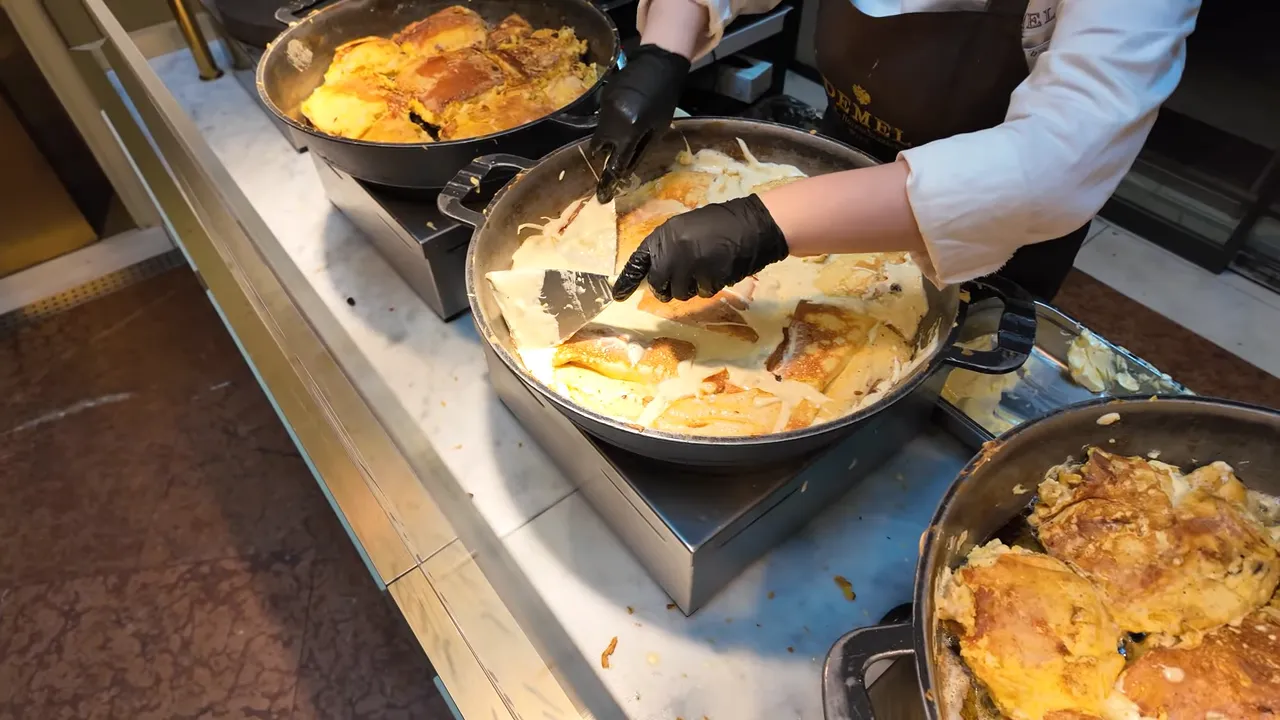 Kaiserschmarrn cooking and being torn apart in a wide pan at Demel