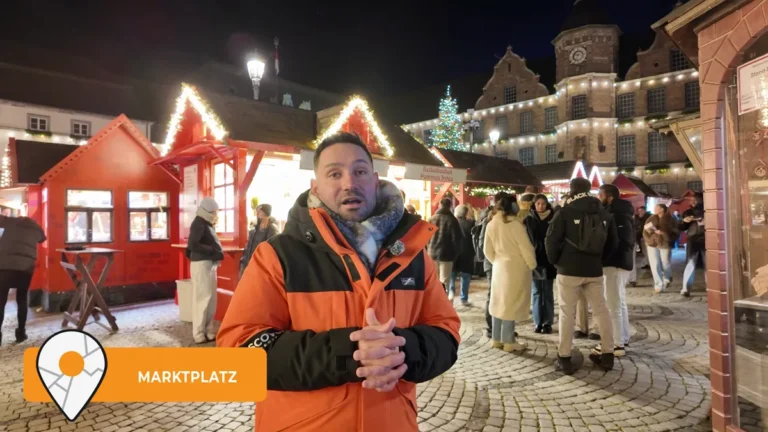 The Christmas market on Marktplatz in Düsseldorf at night, red wooden huts and visitors