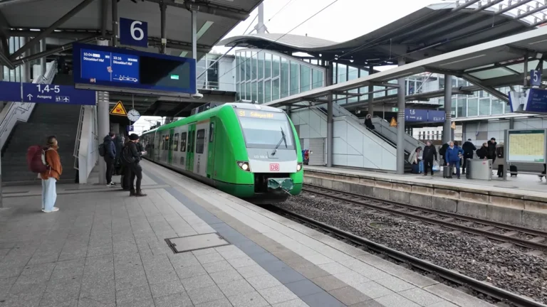 A green and white regional train at platform 6 of Düsseldorf main station, with departure boards overhead