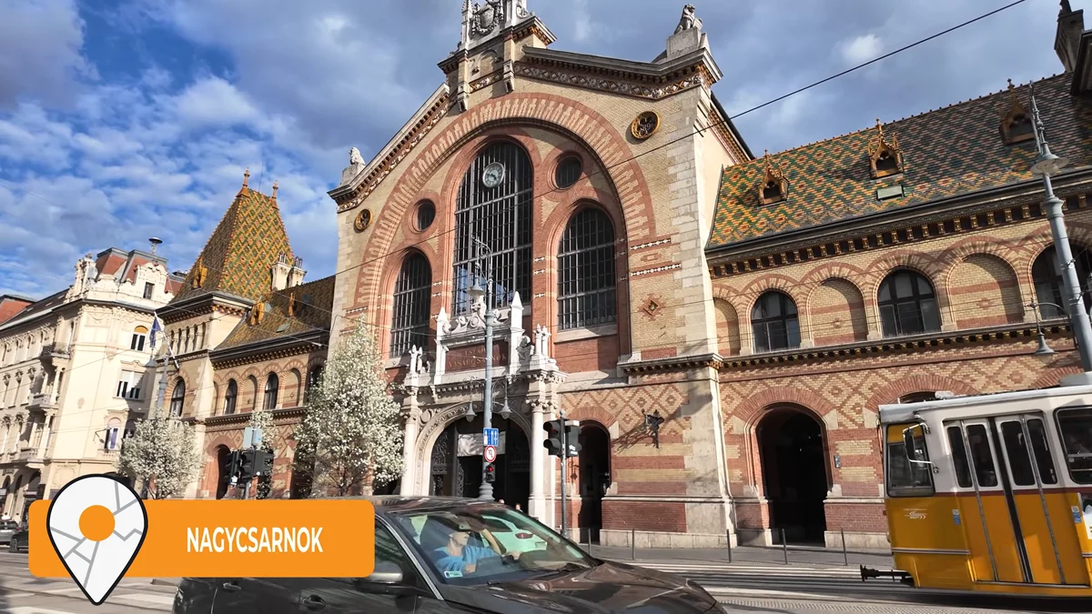 The Great Market Hall building in Budapest with its patterned roof and a yellow tram in front