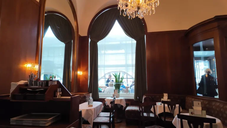 Wood-panelled salon with arched windows and chandeliers at Café Landtmann