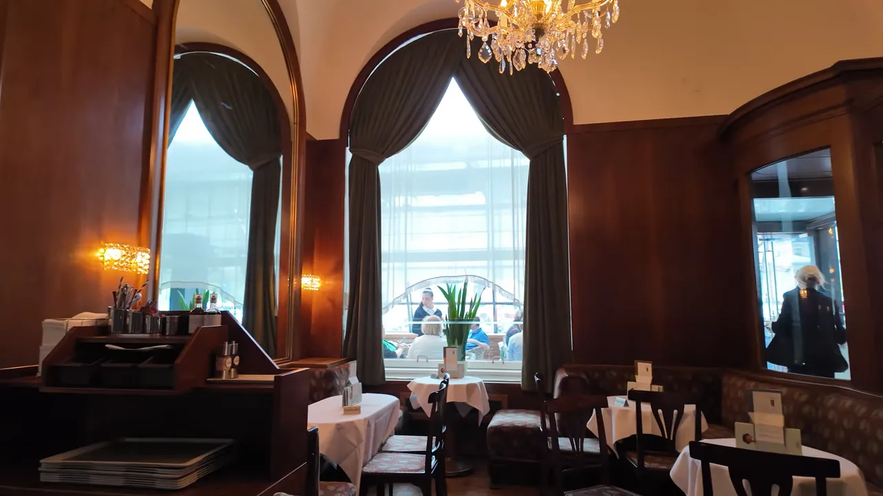 Wood-panelled salon with arched windows and chandeliers at Café Landtmann