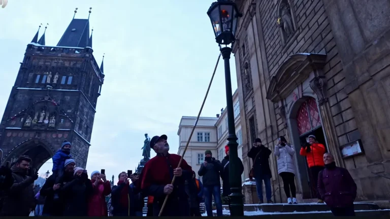 Prag Karlův Köprüsü'nde Noel döneminde gaz lambalarını elle yakan fenerci, Eski Şehir Köprü Kulesi önünde