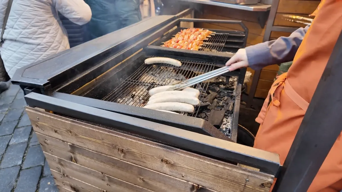 Klobása sausages and skewers grilling over the coals at a Prague Christmas market