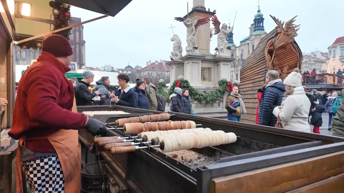 Trdelník dough wrapped on spits turning over the coals at the Old Town Square Christmas market, Prague