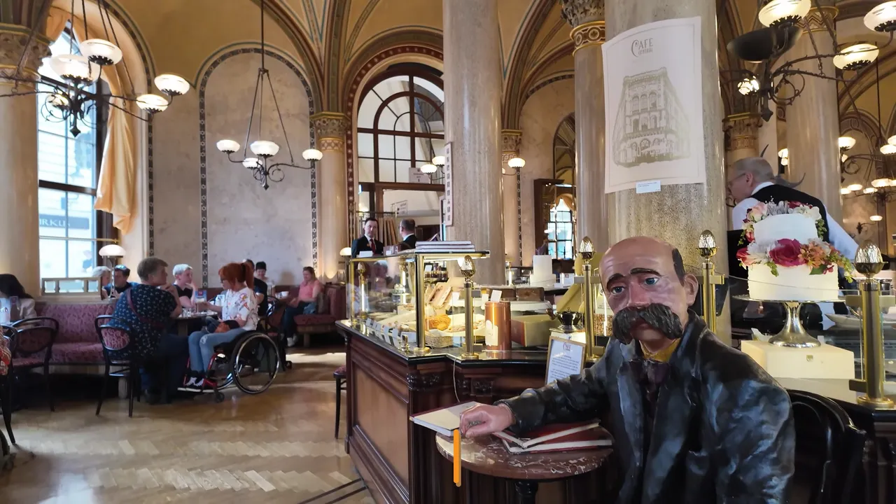 Café Central Viyana'nın kemerli salonunda Peter Altenberg figürü ve pasta tezgahı